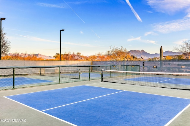 view of tennis court featuring a mountain view and fence