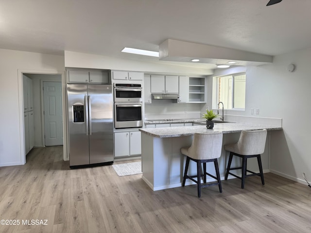 kitchen with light stone counters, stainless steel appliances, kitchen peninsula, and a breakfast bar area