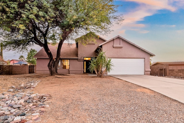 view of front of house with an attached garage, fence, concrete driveway, and stucco siding