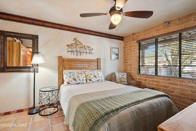 tiled bedroom with ceiling fan and brick wall