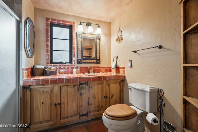 bathroom featuring vanity, tile patterned floors, toilet, and a textured wall