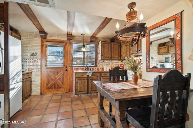 tiled dining room featuring beamed ceiling, sink, and a chandelier