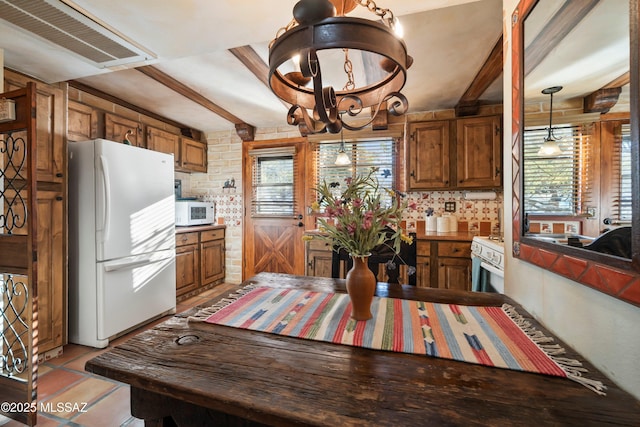 kitchen with an inviting chandelier, white appliances, beam ceiling, and hanging light fixtures