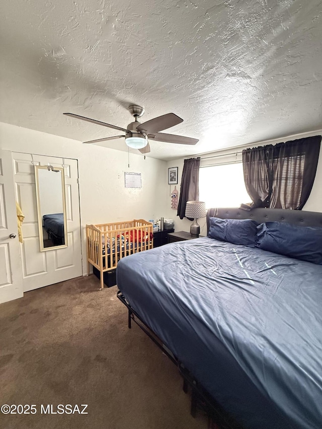 bedroom featuring dark colored carpet, ceiling fan, and a textured ceiling
