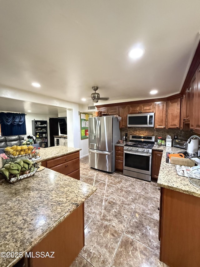 kitchen with stainless steel appliances, sink, light stone counters, and decorative backsplash