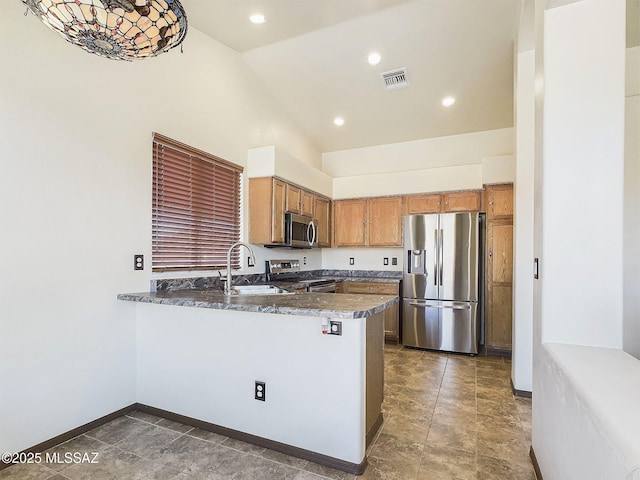 kitchen featuring high vaulted ceiling, sink, dark stone counters, kitchen peninsula, and stainless steel appliances