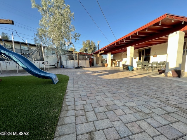 view of property's community with a trampoline, a patio, and a playground