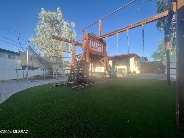 back of property featuring a trampoline, a patio area, a playground, and a lawn