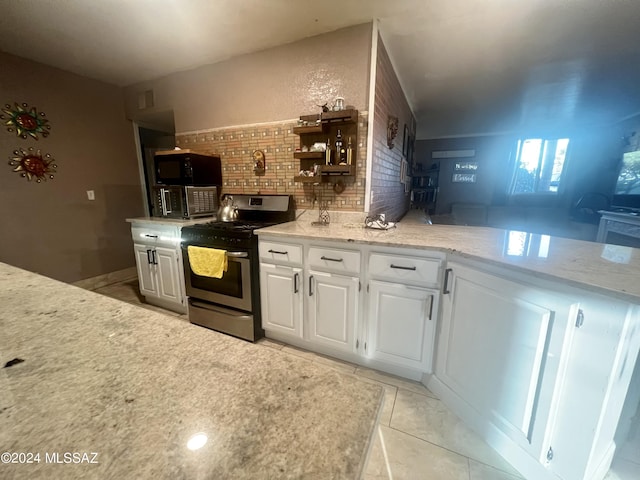 kitchen with decorative backsplash, gas stove, white cabinets, and light tile patterned flooring