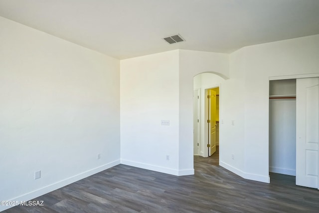 unfurnished bedroom with dark wood-type flooring and a closet