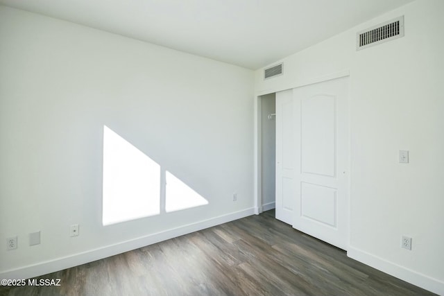 unfurnished bedroom featuring dark hardwood / wood-style flooring and a closet