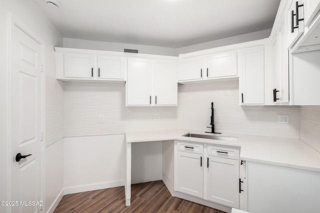 kitchen featuring backsplash, dark hardwood / wood-style flooring, sink, and white cabinets