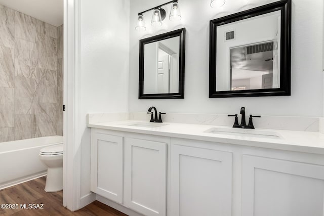 full bathroom featuring vanity, hardwood / wood-style flooring, toilet, and tiled shower / bath