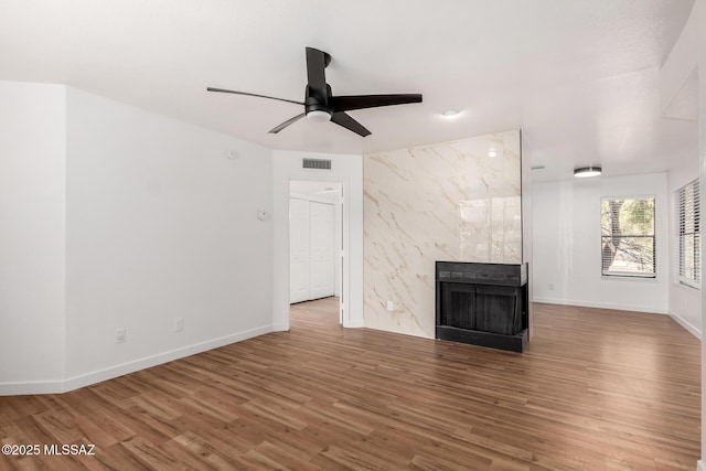 unfurnished living room with a premium fireplace, wood-type flooring, and ceiling fan