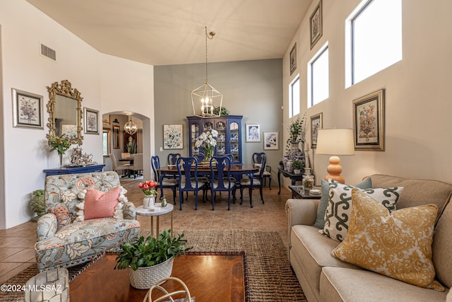 living room with tile patterned flooring, a towering ceiling, and an inviting chandelier