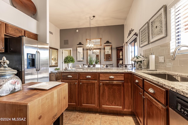 kitchen with sink, light stone countertops, kitchen peninsula, and appliances with stainless steel finishes