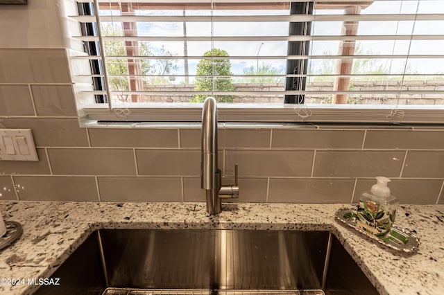 details with sink, backsplash, and light stone counters