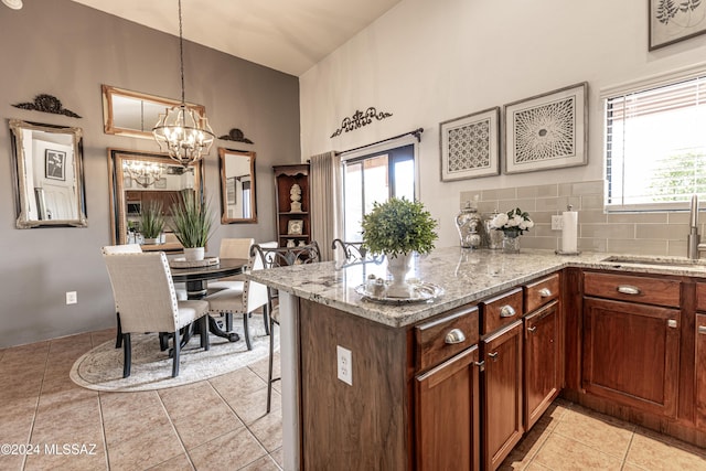 kitchen featuring hanging light fixtures, sink, decorative backsplash, and kitchen peninsula