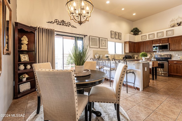 tiled dining space featuring a chandelier, sink, and a high ceiling