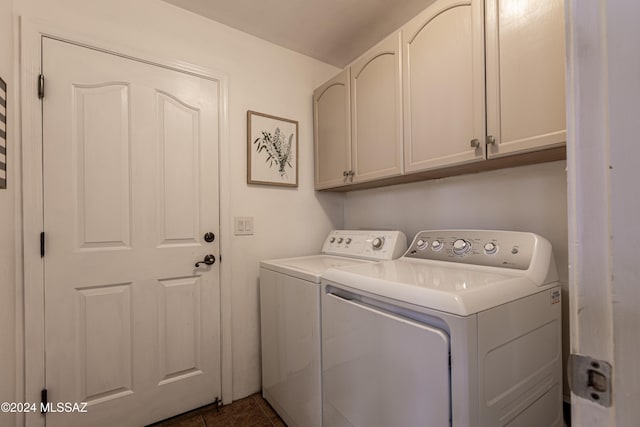 clothes washing area featuring cabinets, dark tile patterned flooring, and washing machine and clothes dryer