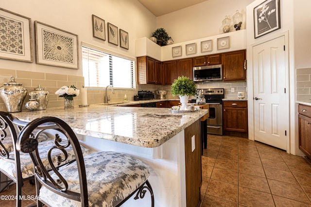 kitchen featuring sink, dark tile patterned floors, stainless steel appliances, a kitchen breakfast bar, and tasteful backsplash