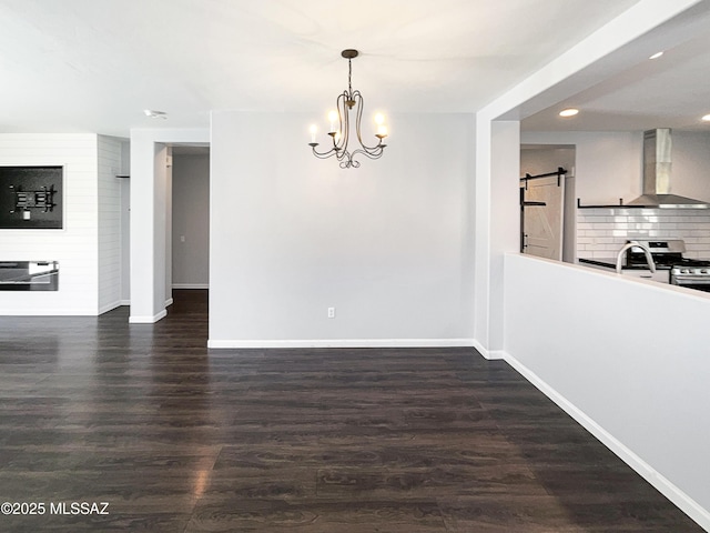 unfurnished dining area with a barn door, dark hardwood / wood-style flooring, and a notable chandelier