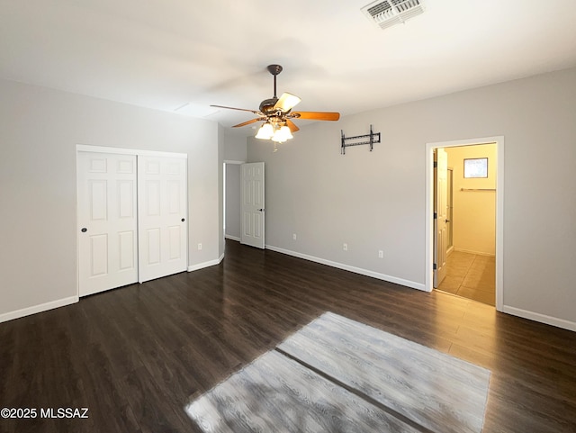 unfurnished bedroom with dark hardwood / wood-style flooring, a closet, ceiling fan, and ensuite bathroom