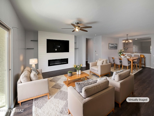 living room with ceiling fan with notable chandelier, a fireplace, and dark hardwood / wood-style floors