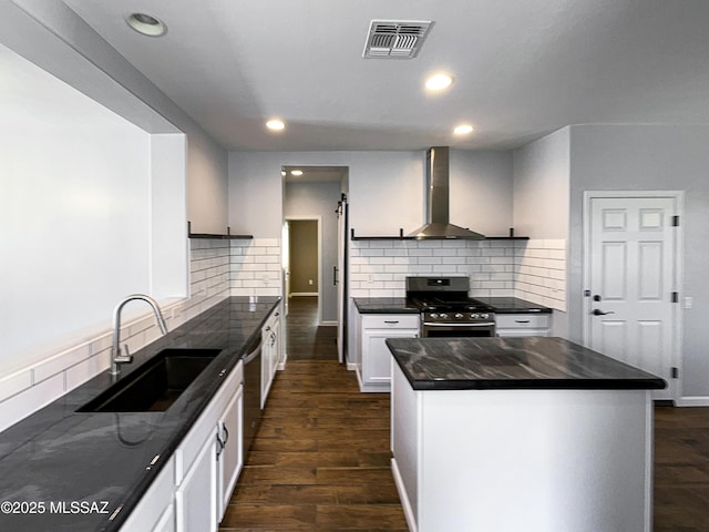 kitchen with sink, white cabinetry, stainless steel appliances, a center island, and wall chimney exhaust hood