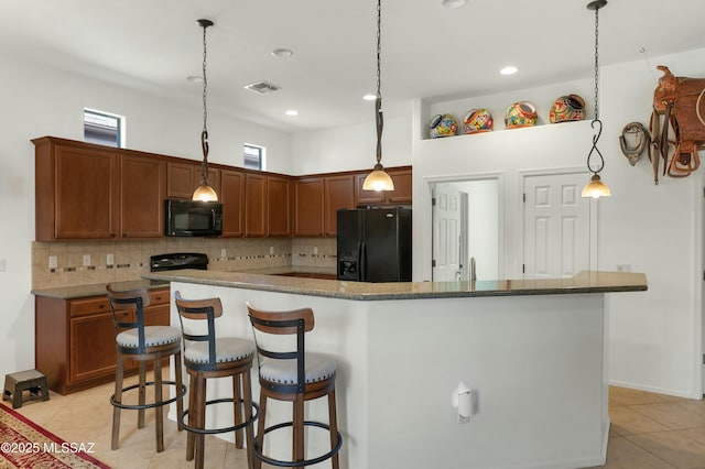 kitchen featuring pendant lighting, a breakfast bar area, backsplash, a center island, and black appliances