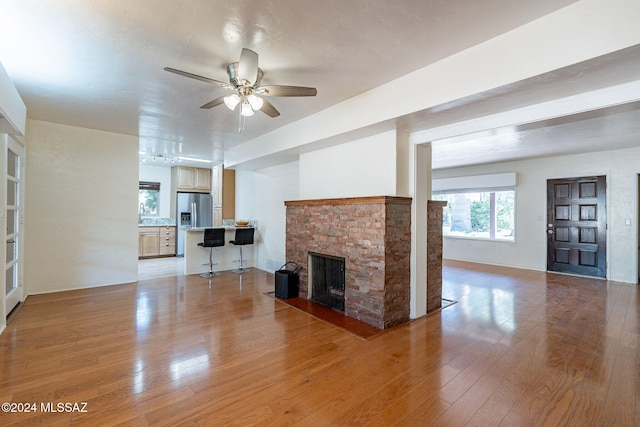 unfurnished living room featuring a fireplace, light hardwood / wood-style flooring, and ceiling fan