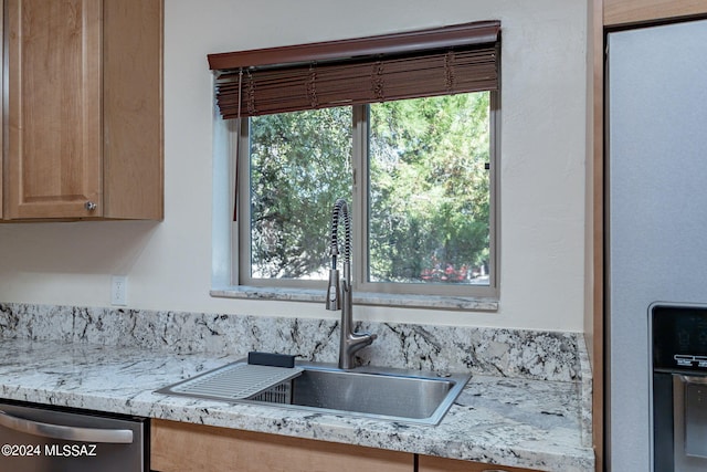 kitchen featuring appliances with stainless steel finishes, light stone countertops, and sink