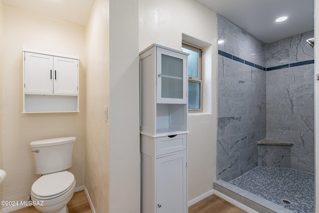 bathroom with wood-type flooring, a tile shower, and toilet