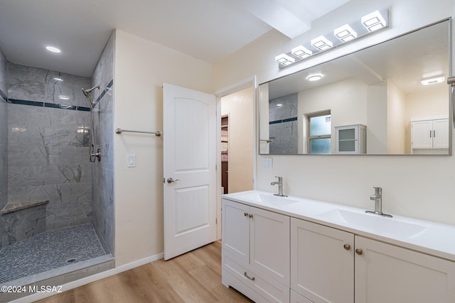 bathroom with hardwood / wood-style flooring, vanity, and a tile shower