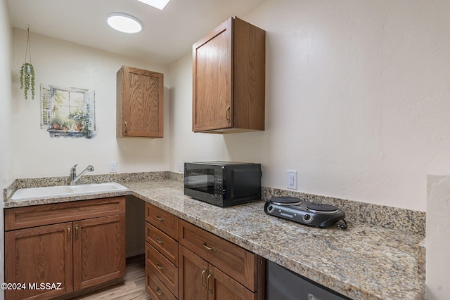 kitchen featuring light stone countertops, sink, and light hardwood / wood-style floors