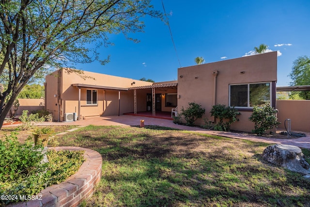 back of property with a yard, a patio, and ac unit