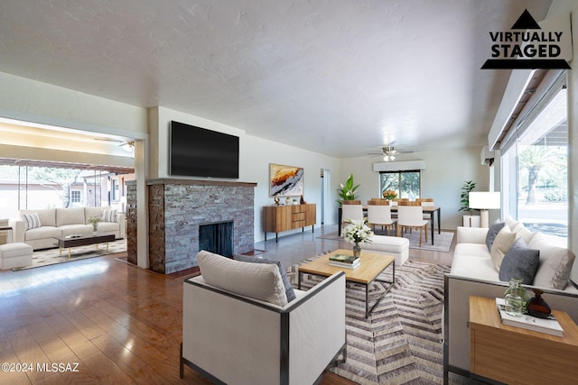 living room featuring ceiling fan, a stone fireplace, and a wealth of natural light