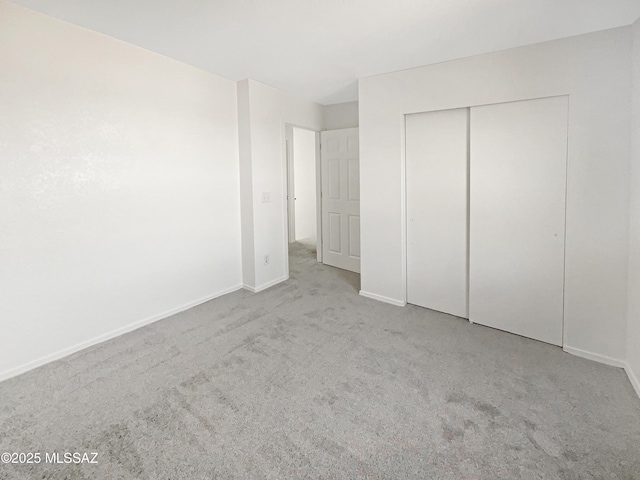 unfurnished bedroom with light carpet and a closet