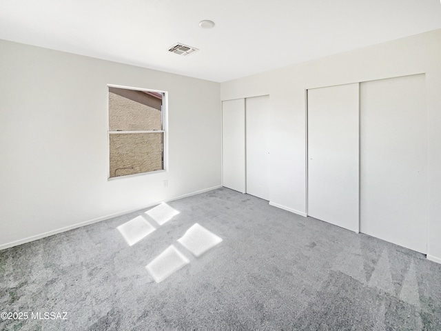 unfurnished bedroom featuring multiple closets and carpet