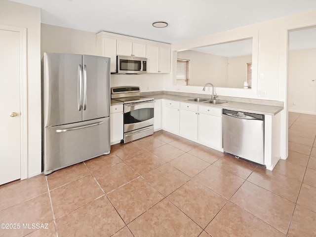 kitchen featuring white cabinetry, sink, light tile patterned floors, and stainless steel appliances