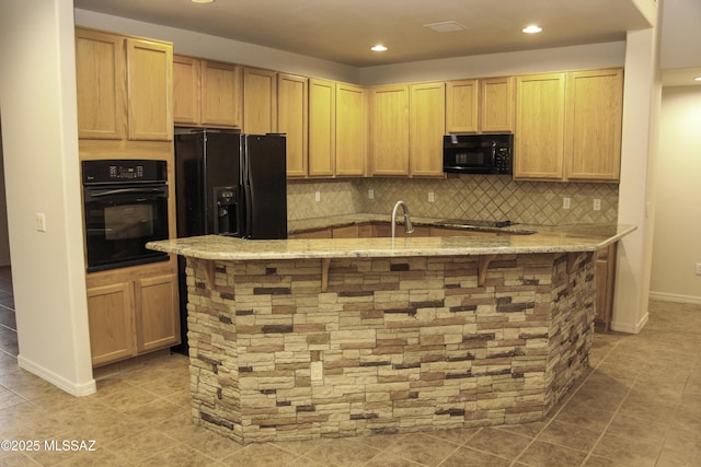 kitchen with tasteful backsplash, a kitchen breakfast bar, black appliances, light stone countertops, and light brown cabinets