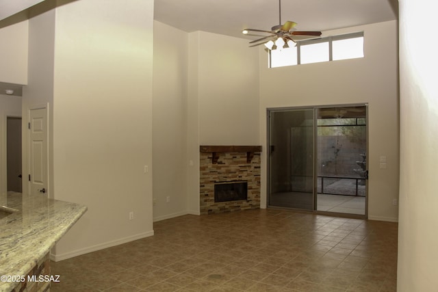 unfurnished living room with a high ceiling, a fireplace, and ceiling fan