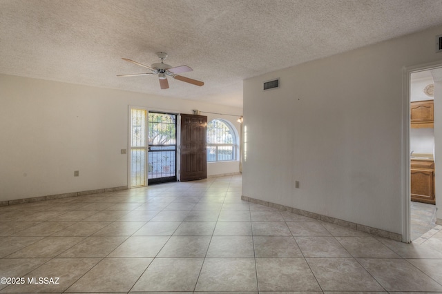 tiled spare room with a textured ceiling and ceiling fan