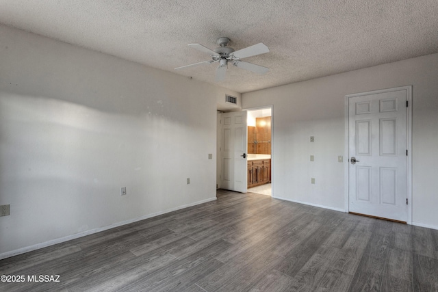 unfurnished bedroom featuring ceiling fan, a textured ceiling, dark hardwood / wood-style flooring, and ensuite bath