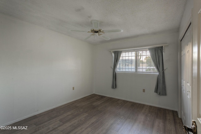 spare room featuring ceiling fan, dark wood-type flooring, and a textured ceiling