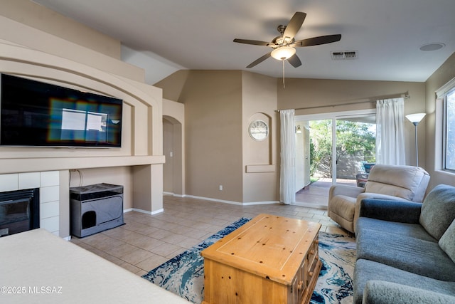 living room with vaulted ceiling, light tile patterned floors, ceiling fan, and a fireplace