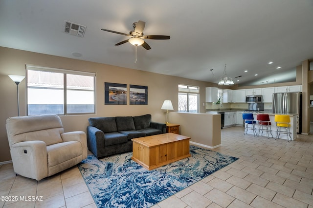 living room with plenty of natural light, light tile patterned floors, lofted ceiling, and ceiling fan