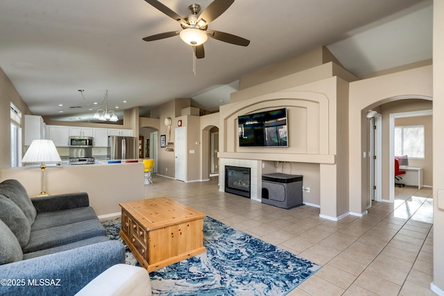 tiled living room featuring a tile fireplace, vaulted ceiling, and ceiling fan