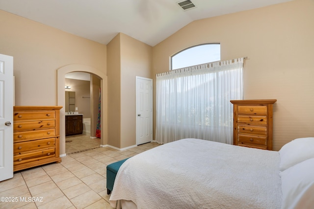 bedroom with light tile patterned flooring, connected bathroom, and vaulted ceiling