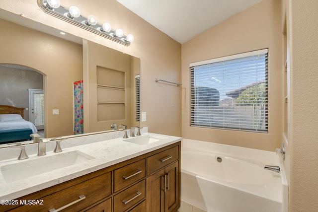 bathroom with vanity, vaulted ceiling, and a washtub